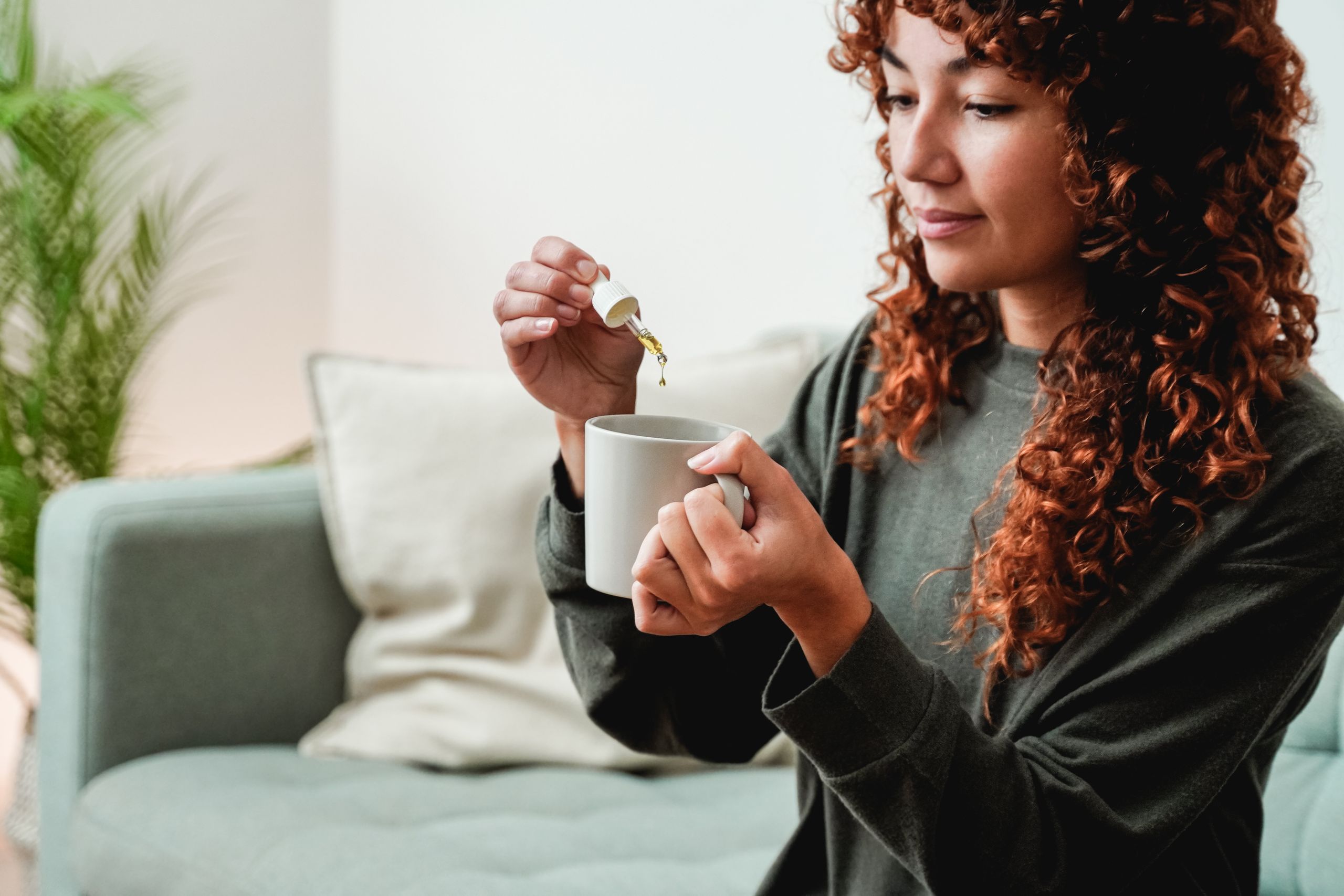 Kvinde der tager CBD olie sammen med sin morgenkaffe